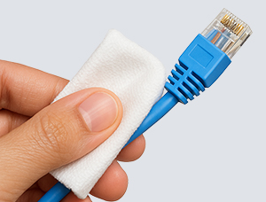 Eine Hand hält ein blaues Ethernet-Kabel und reinigt es mit einem weißen Tuch.