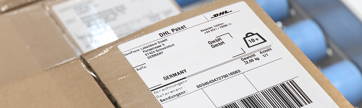 Versandkarton mit aufgeklebtem DHL-Paketetikett, das im Thermodirektdruckverfahren erstellt wurde.