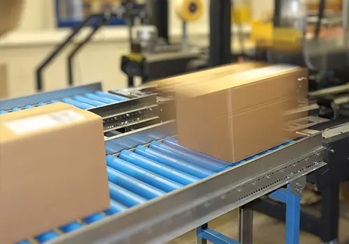 Versandkartons auf einer automatisierten Packstra&szlig;e bei Labelident, aufgenommen in Bewegung f&uuml;r den schnellen t&auml;glichen Versand von &uuml;ber 1.000 Sendungen.