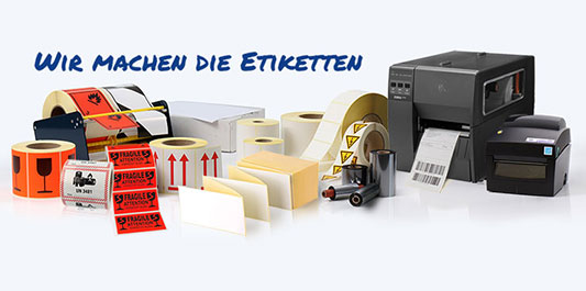 Verschiedene Etiketten auf Rolle, Gefahrgutaufkleber, Drucker und Thermotransferb&auml;nder nebeneinander pr&auml;sentiert &ndash; umfassendes Produktsortiment vom Etikettenhersteller Labelident.